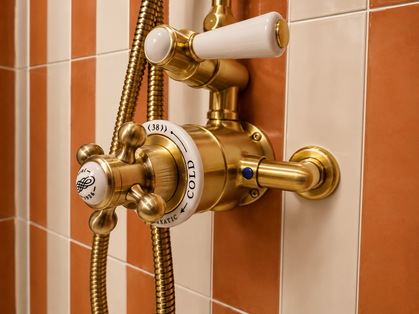 Brass shower controls against striped ceramic tiles